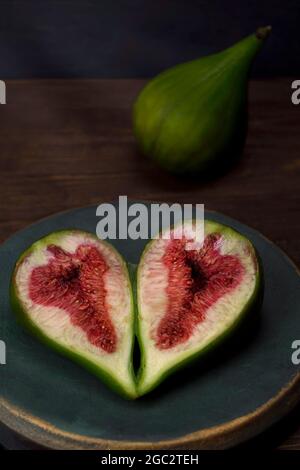 Figues ​​ripe en tranches dans une plaque d'époque en bronze bleu-vert sur une table en bois sous les rayons de lumière. Vue de dessus Banque D'Images