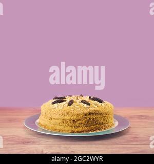 Gâteau fait maison avec crème, noix et pruneaux sur une table en bois sur fond violet avec espace copie Banque D'Images
