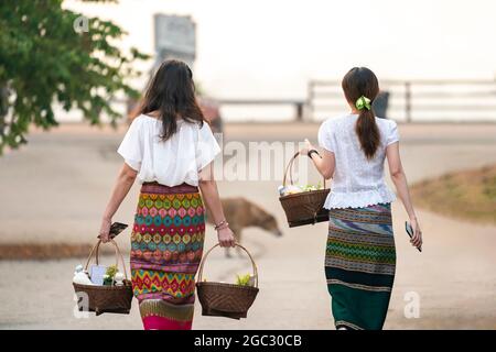 La femme asiatique traditionnelle marche dans la rue pour donner des almes aux moines le matin dans la province de Chiangrai, en Thaïlande. Banque D'Images