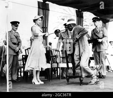 Chevaliers de la reine Cheikh. Avec un genou sur une chaise, Seiyid Bubakr Bin Sheikh KAF, conseillère de l'état de Kathiri à Aden est, a reçu l'accolade de la reine Elizabeth lors d'une investiture en plein air lors de sa visite à Aden. C'était la première fois, au cours de la tournée royale, que la Reine avait tenu une investiture en public, le 27 avril 1954 Banque D'Images