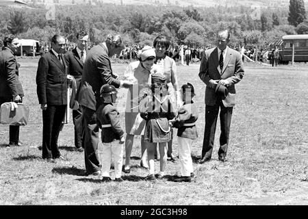 Pucon, Chili: Trois enfants locaux (deux garçons et une fille), robes comme mascottes de brigade de feu, présenter la reine Elizabeth II avec un bouquet ici le 15 novembre. Le ministre des Affaires étrangères Valdes prend le bouquet des enfants. La Reine accommodée par le prince Philip (à l'extrême droite) est en visite d'État de 8 jours au Chili. 19 novembre 1968 Banque D'Images