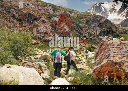 Les femmes avec des sacs à dos et des bâtons scandinaves grimpent dans les montagnes Banque D'Images