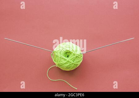 Balles de tricot vert et aiguilles de tricot vue de dessus sur fond rose avec espace de copie. Tricotage écologique. Banque D'Images