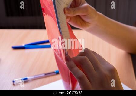 Les mains de femmes en gros plan empilent des feuilles de papier griffées en rose, dossier rouge, affaires, concept de formation. Banque D'Images