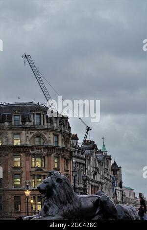 UNE PHOTO NOCTURNE DE L'UN DES LIONS DE PIERRE DE LA PLACE TRAFALGAR À LONDRES, AVEC UN HORIZON DE DARKAND MENAÇANT Banque D'Images