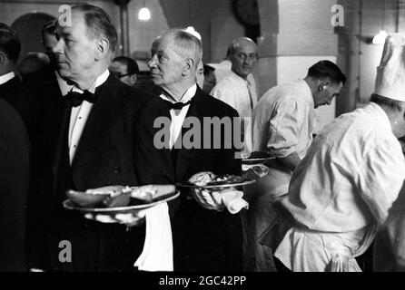 Dans les coulisses d'un banquet d'État. Banquet de retour pour la reine Elizabeth II au Mansion House, Londres, après sa visite du Commonwealth en 1954. La société de restauration de Ring & Brymer (Birch's) Ltd a géré la restauration à chaque banquet de Coronation donné par la Corporation of London depuis le Coronation de la reine Victoria et a occupé plus de têtes couronnées que n'importe quelle autre entreprise du monde. 19 mai 1954 photos: Ils sont éteints! Les serveurs sortent avec le premier plat - les poires et les crevettes avocat. Banque D'Images