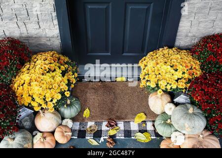 Tapis de porte de bienvenue du porche avant qui a été décoré pour l'automne avec des citrouilles et des mamans blanches, orange et grises. Banque D'Images