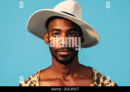 Gros plan portrait d'un beau homme en chapeau sur fond bleu Banque D'Images