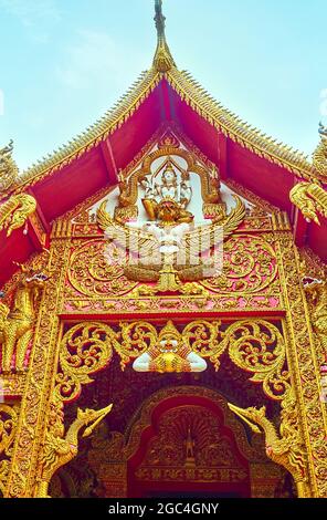 Détail de la façade du temple de la famille Wat Phrao (Wat Lum) de Wat Phra que Lampang Luang avec l'oiseau doré Garuda et les cygnes de Hong, entouré par la belle P florale Banque D'Images