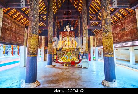 LAMPANG, THAÏLANDE - 8 MAI 2019: Le bois médiéval Viharn Nam Taem de Wat Phra que Lampang Luang, avec des piliers en teck décorés et l'image dorée de Bouddha Banque D'Images