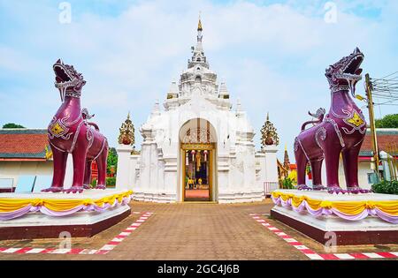 La porte d'entrée de Wat Phra que le monastère royal de Hariphunchai avec de belles moulures et des lions de Singha violets en face de lui, Lamphun, Thaïlande Banque D'Images