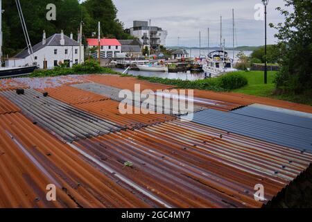 Vue sur le toit d'un atelier en fer ondulé rouillé, avec activité sur la écluse de Crinan Banque D'Images