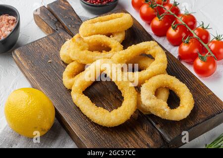 Rondelles de calamars panées cuites au four, sur plateau de service, sur fond de table en pierre blanche Banque D'Images