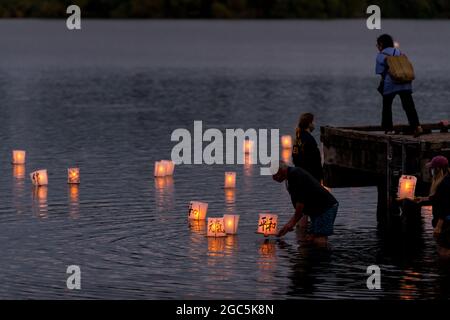 Seattle, États-Unis. 6 août 2021. Au crépuscule, les gens flottent des lanternes en papier de riz au mémorial du 76e anniversaire de Hiroshima à Hope. Les gens se rassemblent chaque année sur les rives du lac Green, juste au nord du centre-ville de Seattle, ils éclairent les lanternes en papier de riz avec des bougies dans les mémoires des victimes de l'attentat à la bombe nucléaire d'Hiroshima pendant la deuxième Guerre mondiale. Crédit : James Anderson/Alay Banque D'Images