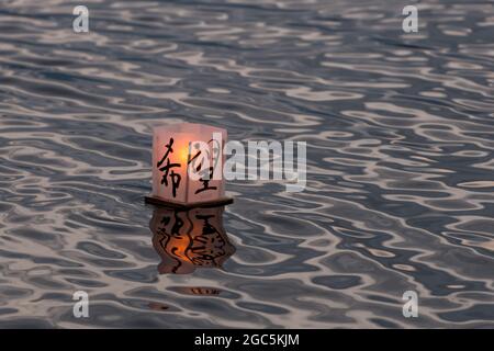 Seattle, États-Unis. 6 août 2021. Au crépuscule, une lanterne flottante en papier de riz au mémorial du 76e anniversaire de Hiroshima à Hope. Les gens se rassemblent chaque année sur les rives du lac Green, juste au nord du centre-ville de Seattle, ils éclairent les lanternes en papier de riz avec des bougies dans les mémoires des victimes de l'attentat à la bombe nucléaire d'Hiroshima pendant la deuxième Guerre mondiale. Crédit : James Anderson/Alay Banque D'Images