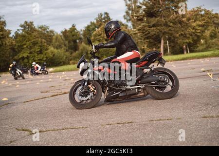 Un motard masculin portant un costume de course en cuir de protection avec une moto ou une moto rouge sur une route à ciel ouvert. L'image est prise en mode HDR et composite. L'im Banque D'Images