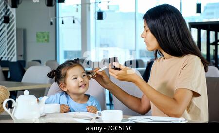 Petite fille aide maman à appliquer le maquillage. Banque D'Images