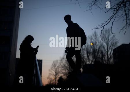 Silhouette d'une fille et d'un gars. Marchez la nuit. Les jeunes se reposent dans le noir. Rencontrer un gars et une fille. La silhouette d'un homme. Banque D'Images