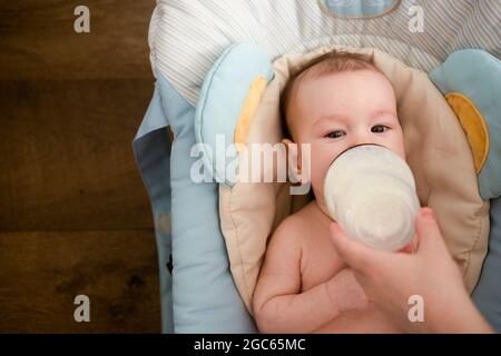 allaiter un bébé avec un biberon, le bébé regarde l'appareil photo Banque D'Images