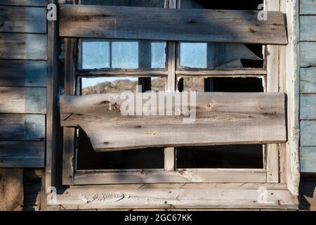 Ancienne fenêtre cassée couverte de planches de maisons en bois détruites et abandonnées Banque D'Images