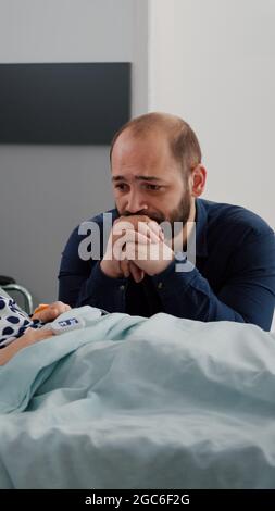 Enfant malade, fille portant un tube nasal à oxygène et un oxymètre sur le pouls cardiaque de surveillance du doigt pendant le sommeil. Un père inquiet pleure à côté du lit pendant la période de récupération dans la salle d'hôpital, traitement médical Banque D'Images