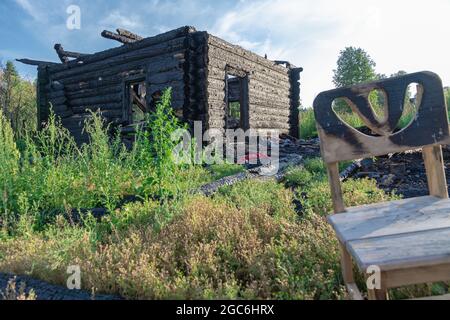 Une vieille maison en rondins brûlée dans le village lors d'une belle journée d'été contre le ciel bleu. Gros plan Banque D'Images