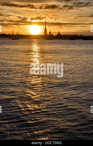 Coucher de soleil sur la rivière Neva. Le soleil se couche sous l'horizon. Le ciel et l'eau sont colorés en rouge. Banque D'Images