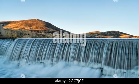 Eau en cascade au-dessus d'un barrage de dérivation à creek dans les contreforts du Colorado, paysage de printemps au lever du soleil Banque D'Images