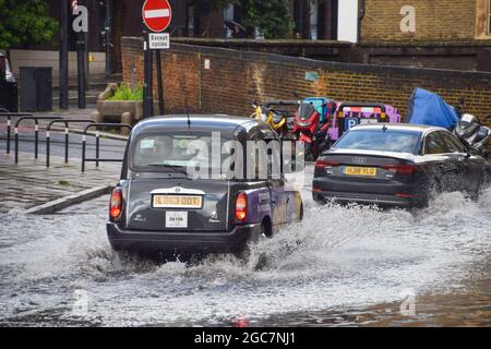 Londres, Royaume-Uni. 7 août 2021. Un taxi londonien éclabousse à travers une Farringdon Lane inondée après une journée de forte pluie dans la capitale (Credit: Vuk Valcic / Alamy Live News) Banque D'Images