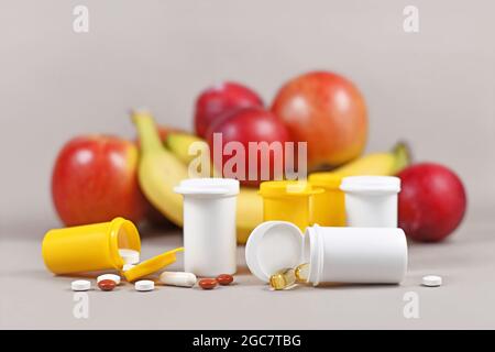 Compléments nutritionnels alimentaires capsules et pilules avec des bouteilles en plastique devant les fruits Banque D'Images