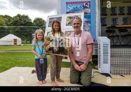 North Berwick, East Lothian, Écosse, Royaume-Uni, 7 août 2021. Gordon Buchanan à Fringe-by-the-Sea : Gordon Buchanan, célèbre photographe de la faune et réalisateur de la série télévisée « Family & Me », signe des copies de ses photos de la faune, ici avec Aila Reid, âgée de 5 ans, et Etta Reid, âgée de 8 ans et l'une de ses photos d'ours Banque D'Images