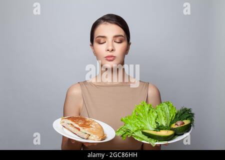 Portrait d'une femme brunette réfléchie 20s avec une alimentation saine et malsaine. Concept de régime alimentaire et de mode de vie sain Banque D'Images