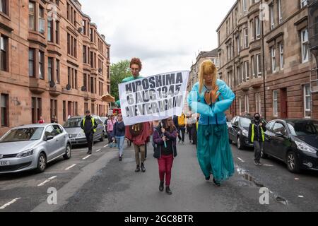 Glasgow, Écosse, Royaume-Uni. 7 août 2021. Un panneau disant Hiroshima 6 août 1945 jamais de nouveau est porté dans la parade du Carnaval de Govanhill. Le défilé de cette année comprend des groupes communautaires, un joueur de cornemuse, des batteurs, des danseurs, des jongleurs, Des patineurs à roulettes et un groupe de cuivres commencent tous à Govanhill Park et traversent les rues de Govanhill pour terminer à Queen's Park Arena. Credit: SKULLY/Alay Live News Banque D'Images