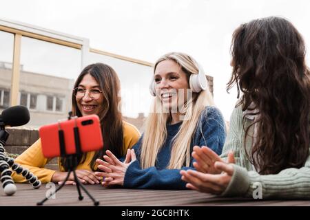 Jeunes diverses personnes streaming audio podcast en ligne extérieur à la maison studio - amis enregistrement avec téléphone mobile - Focus sur le visage de femme centrale Banque D'Images