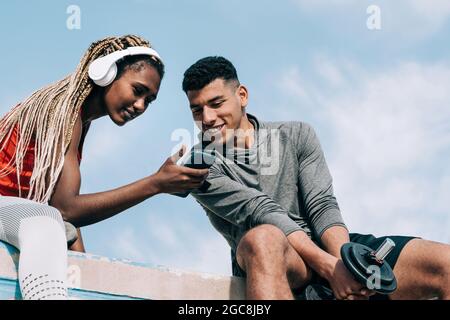 Sport multiracial personnes regardant la vidéo sur le téléphone mobile après séance d'entraînement en plein air dans la ville - Focus sur le visage de l'homme africain Banque D'Images