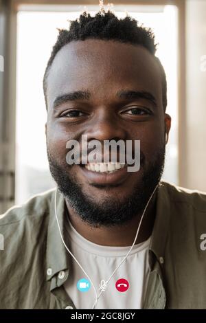 Écran d'un jeune homme afro-américain faisant des appels vidéo avec un téléphone mobile en intérieur au bar-restaurant - application de conférence en ligne, distance sociale Banque D'Images