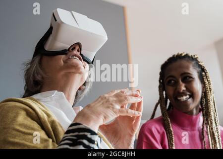 Personnes multiraciales utilisant un casque de réalité virtuelle vr en intérieur à la maison - concentrez-vous sur le visage d'une femme âgée Banque D'Images