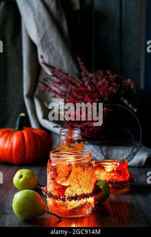 Lanterne d'automne faite d'un pot en verre décoré de feuilles colorées et d'une couronne de bruyère. Bougie à l'intérieur. Banque D'Images