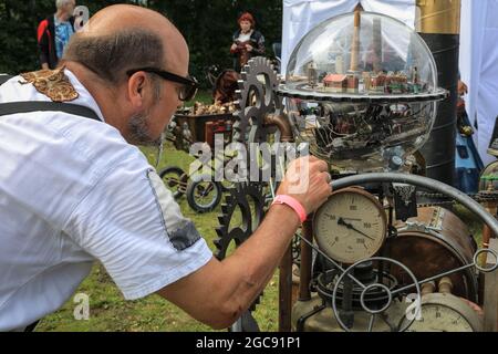 Schiffshebewerk Henrichenburg, Waltrop, Allemagne, 7 août 2021. Un passionné de steampunk étudie des machines de fantaisie au festival. Les fans et les visiteurs de steampunk, dont beaucoup sont en costumes rétro-futuristes et en tenues de steampunk, se réunissent pour le festival du marché du Jubilé de la Souteampunk au site historique de Henrichenburg, une partie du parc de Waltrop-écluse sur le canal Dortmund-EMS, devenu un musée industriel. L'ancien cadre en fer, les tours de contrôle, les maisons de machines et le musée forment une toile de fond atmosphérique pour le festival.Credit: Imagetraceur/Alamy Live News Banque D'Images