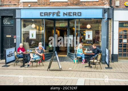 Les gens mangeant et buvant à s'asseoir dehors au café Caffe Nero sur la rue haute dans la ville Berkshire de Newbury Banque D'Images