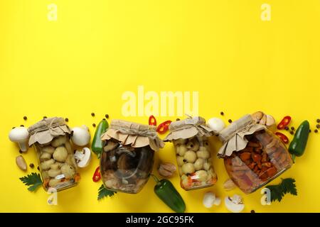 Pots aux champignons marinés sur fond jaune Banque D'Images