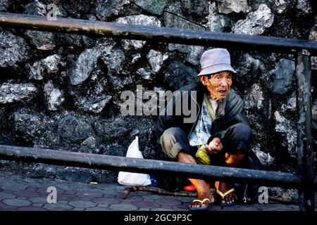 BAGUIO, PHILIPPINES - 18 décembre 2016 : un vieil homme assis dans la rue de la ville de Baguio, Philippines Banque D'Images