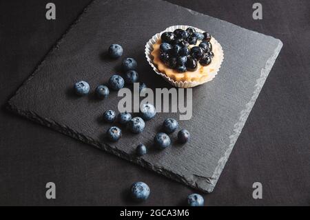 La tarte aux myrtilles est sur fond noir de pierre naturelle. Encore plus de vie avec des gâteaux doux aux baies sauvages sur fond sombre Banque D'Images