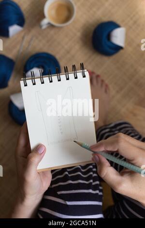 Gros plan d'une femme avec des ongles bien soignés dessin d'un dessin avec un crayon sur un cahier en spirale. Banque D'Images