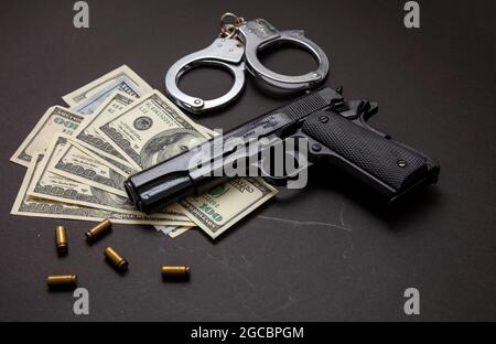 Crime et droit. Pistolet et balles 9 mm, menottes et billets en dollars américains sur fond noir. L'argent criminel et la punition, closéeu Banque D'Images