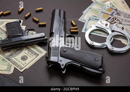 L'argent criminel et la peine. Pistolets et obus de balle 9 mm, menottes et billets en dollars américains sur fond noir. Crime et droit, Banque D'Images