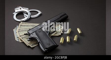 Crime et droit. Pistolet et balles 9 mm, menottes et billets en dollars américains sur fond noir. L'argent criminel et la punition, closéeu Banque D'Images