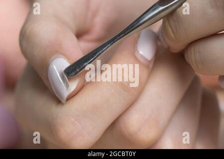 Retirez le produit à polir pour gel à l'aide d'un poussoir métallique. La femme retire le gel lustrant shellac des ongles à l'aide d'un poussoir, manucure à la maison. Retrait du gel polonais de na Banque D'Images