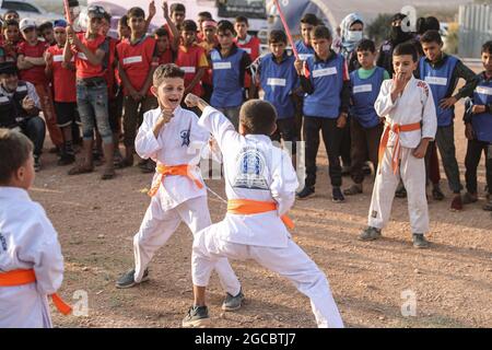 Idlib City, Syrie. 07e août 2021. Deux enfants syriens jouent un match de karaté dans le cadre d'une petite manifestation de style olympique organisée à l'intention des enfants déplacés par des volontaires de l'organisation de secours Violet. L'événement sportif est organisé en conjonction avec les Jeux Olympiques de Tokyo en 2020 pour attirer l'attention sur les conditions à l'intérieur des camps de réfugiés de ceux qui ont été contraints à des déplacements internes à la suite du conflit civil syrien. Credit: Aras Alkharboutli/dpa/Alamy Live News Banque D'Images