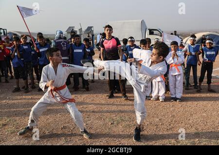 Idlib City, Syrie. 07e août 2021. Deux enfants syriens jouent un match de karaté dans le cadre d'une petite manifestation de style olympique organisée à l'intention des enfants déplacés par des volontaires de l'organisation de secours Violet. L'événement sportif est organisé en conjonction avec les Jeux Olympiques de Tokyo en 2020 pour attirer l'attention sur les conditions à l'intérieur des camps de réfugiés de ceux qui ont été contraints à des déplacements internes à la suite du conflit civil syrien. Credit: Aras Alkharboutli/dpa/Alamy Live News Banque D'Images